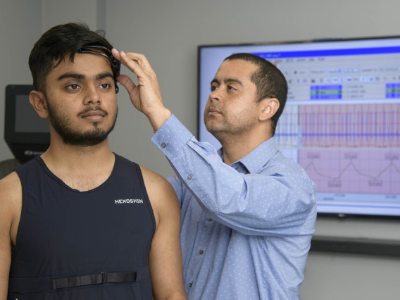 Dr. Almeida attaches sensors to a research study participant. The sensors will give researchers real-time physiological data as the participant exercises on a treadmill.