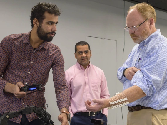 Two people experiment with sensors while sensor lab manager looks on.