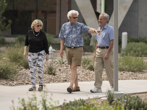 Three older adults walk around the UAHS campus