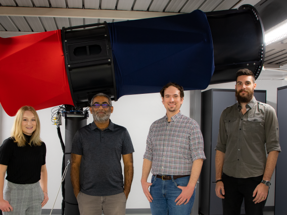 Four people in front of large telescope