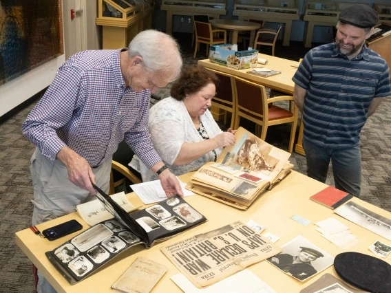 Lowell and Wendy Franklin peruse the materials they donated with associate librarian Trent Purdy, curator of the USS Arizona Collection