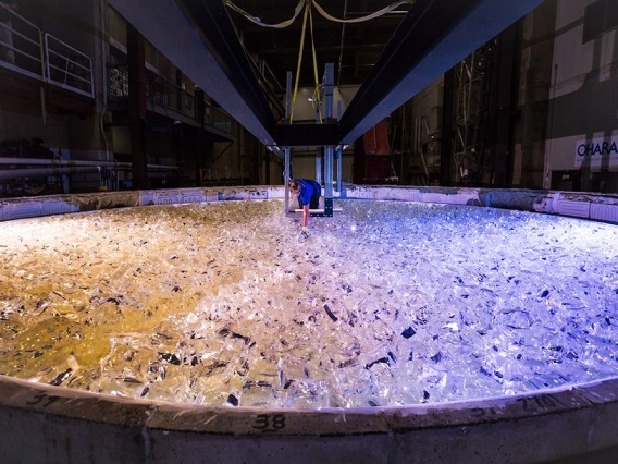 A staff member at the UArizona Richard F. Caris Mirror Lab is seen placing chunks of glass into the mold of the rotating furnace. 